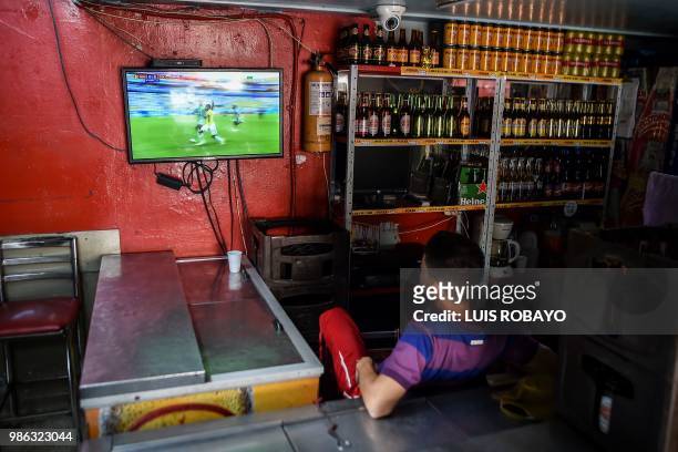 Man watches the World Cup match between Colombia and Senegal on TV at a popular market in Cali, Colombia, on June 28, 2018. - Colombia beat Senegal...
