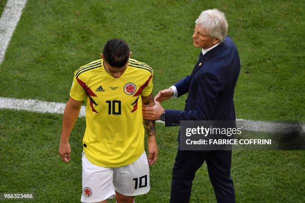 Colombia's midfielder James Rodriguez leaves the football pitch due to an injury as he is conforted by Colombia's coach Jose Pekerman during the...