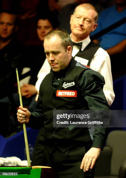John Higgins of Scotland eyes up a shot in front of Steve Davis of England during the Betfred.com World Snooker Championships match at The Crucible...