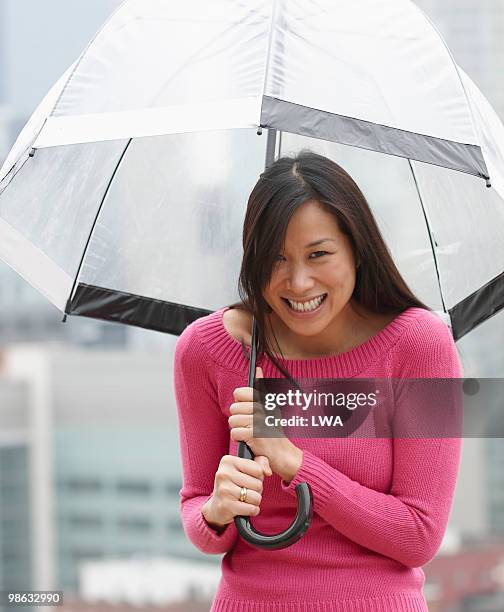 smiling woman under umbrella during rain shower - woman smiling facing down stock pictures, royalty-free photos & images