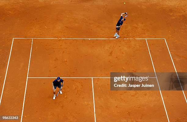 Bob Bryan of the US serves the ball flanked by Mike Bryan during the quarter final doubles match against Mariusz Fyrstenberg and Marcin Matkowski of...