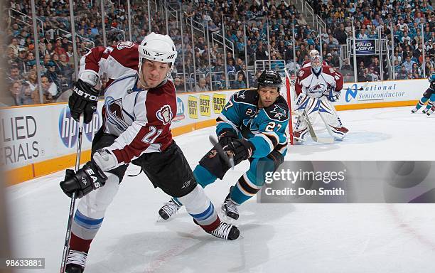 Scott Hannan of the Colorado Avalanche plays the puck against Manny Malhotra of the San Jose Sharks in Game Two of the Western Conference...