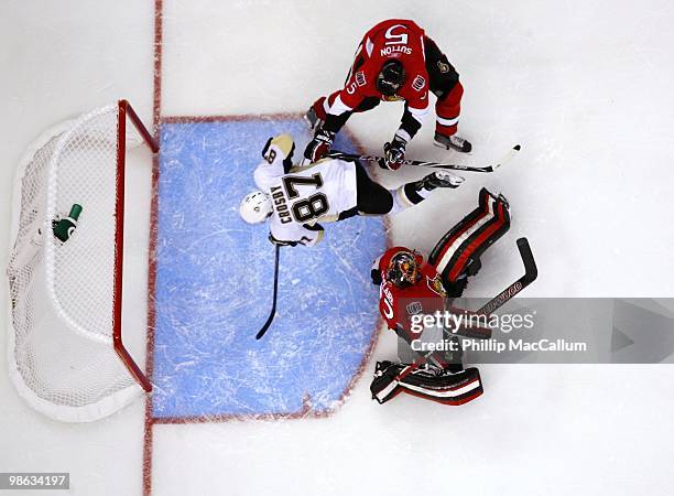 Goaltender Pascal Leclaire of the Ottawa Senators makes a save as teammate Andy Sutton cross checks Sidney Crosby of the Pittsburgh Penguins in Game...