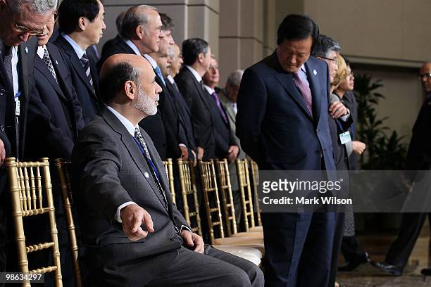 Chairman of the Federal Reserve Ben Bernanke points out an assigned seat while participateing in a group photo at the International Monetary Fund on...