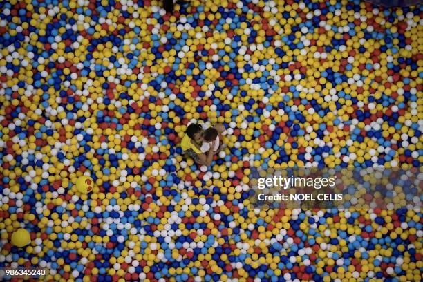 Children play in a pool filed with small balls at a mall in Manila on June 28, 2018.