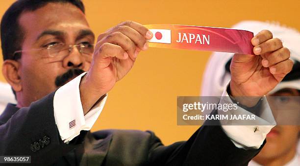 General-Secretary of the Asian Football Confederation Alex Soosay holds up a slip of paper bearing the name Japan during the final draw for the 2011...