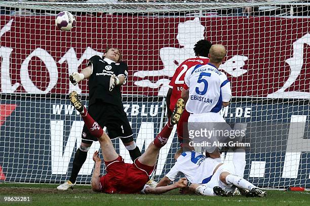 Goalkeeper Tobias Sippel of Kaiserslautern tries to make a save against Gardar Johannsson and Tim Sebastian of Rostock during the Second Bundesliga...