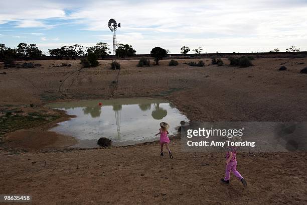 Natalie and Samantha Turner play near a farm dam with low water on a trip with their dad to clean out watering troughs and check on windmills on...