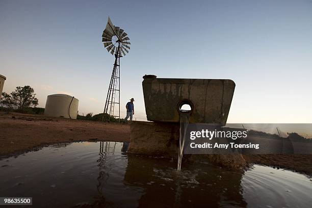 Darren Turner cleans watering troughs and checks on windmills on his farm February 9, 2008 in Ivanhoe, New South Wales, Australia. The Turners, like...