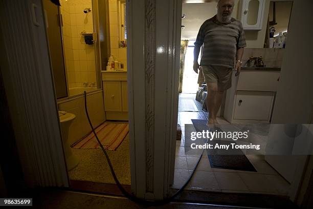 Peter Leonard uses a garden hose to siphon water saved in his tub from his shower to water his lawn February 28, 2008 in Adelaide, South Australia,...