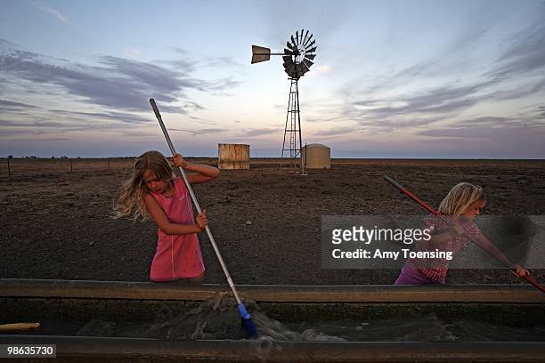 Natalie and Samantha Turner help their dad clean out a watering troughs and check on windmills February 10, 2008 in Ivanhoe, New South Wales,...