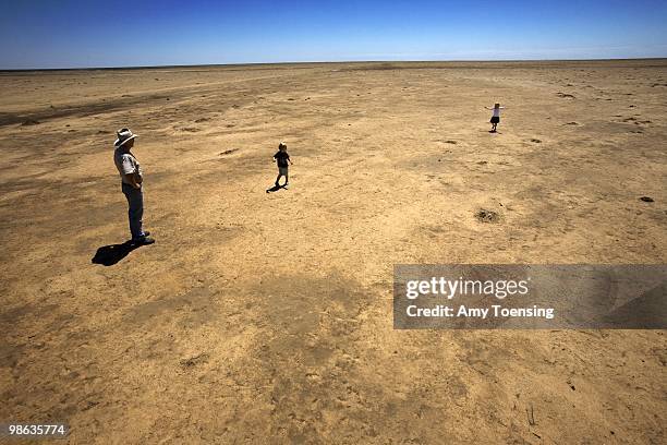 Simon Booth plays with his kids, Claire and Ryan in a dried up paddock on their farm February 7, 2008 in Balranald, New South Wales, Australia. Simon...