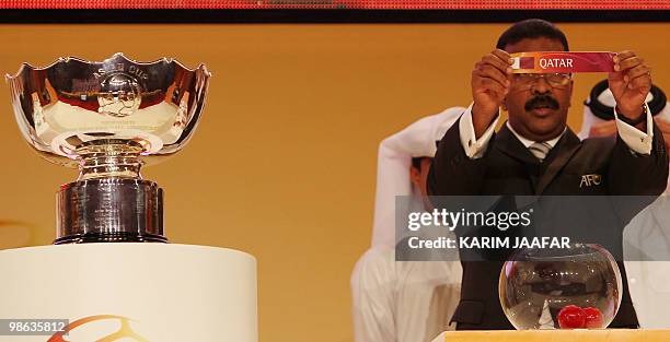 General-Secretary of the Asian Football Confederation Alex Soosay holds up a slip of paper carrying the name Qatar during the final draw for the 2011...