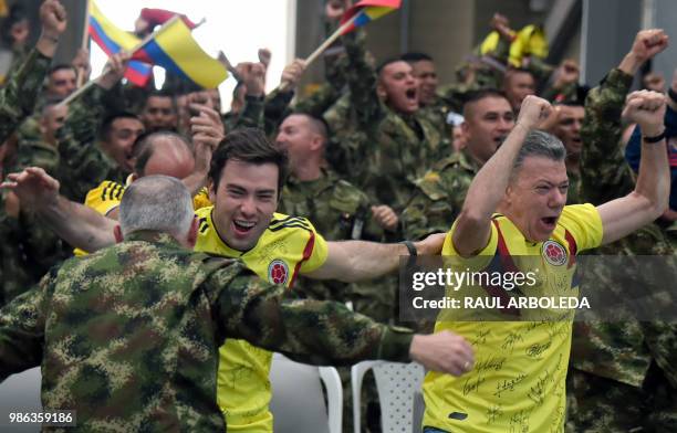 Colombian President Juan Manuel Santos along with his son Esteban and members of the Colombian army celebrate as they follow on a screen the FIFA...