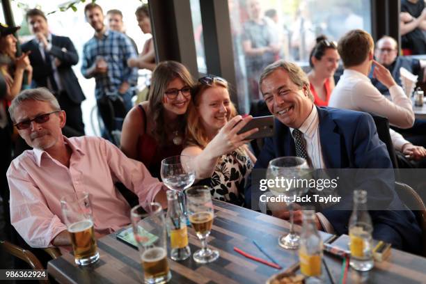 People take a selfie with Nigel Farage, Member of the European Parliament and former Leader of the UK Independence Party as he watches England take...