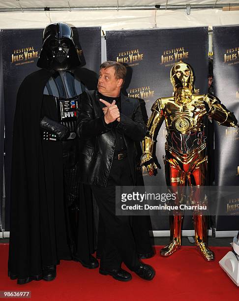 Actor Mark Hamill poses with C-3PO and Darth Vader as he attends a Tribute to Star Wars V during the 18th Adventure Film Festival at Le Grand Rex on...