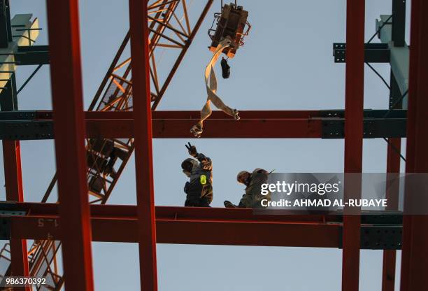 Iranian construction workers walk on a steel I-beam at a site for a future bank tower in the Iraqi capital Baghdad's central Abu Nawas street on June...