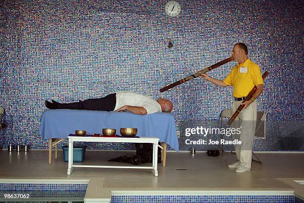 Frank Willis, a vibrational energy healer, uses an Aborigine didgeridoo to blow vibrations over Randall Rodriguez to readjust him during the...