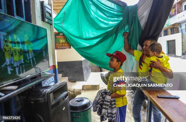 People watch the World Cup match between Colombia and Senegal on TV at the Comuna Popular 1 in Medellin, Colombia, on June 28, 2018. Colombia beat...