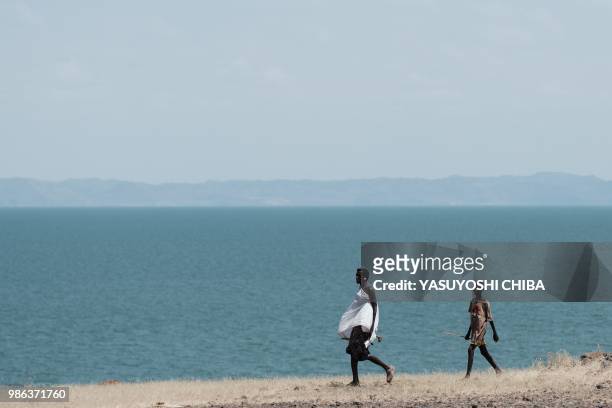 People walk near the Lake Turkana, the world's largest desert lake, in nothern Kenya on June 28, 2018.