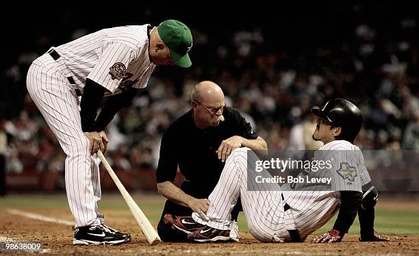 Kazuo Matsui of the Houston Astros is attended to by assisstant trainer Rex Jones and manager Brad Mills as he lays on the ground after hitting a...