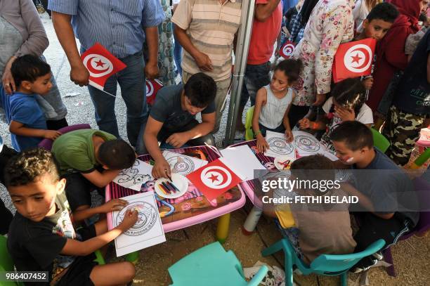 Tunisian children colour drawings of their national football federation on the sidelines of a fan fest to watch the Russia 2018 World Cup Group G...