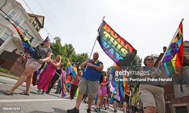 Adam Beatty of Biddeford, center, carries a flag stating Born This Way while marching along High Street in the Portland Pride parade.
