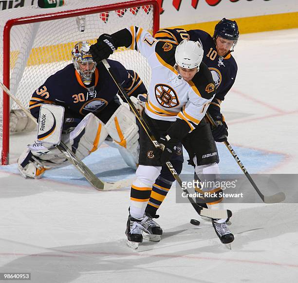 Milan Lucic of the Boston Bruins deflects the puck between his legs as Henrik Tallinder and Ryan Miller of the Buffalo Sabres defend in Game Five of...