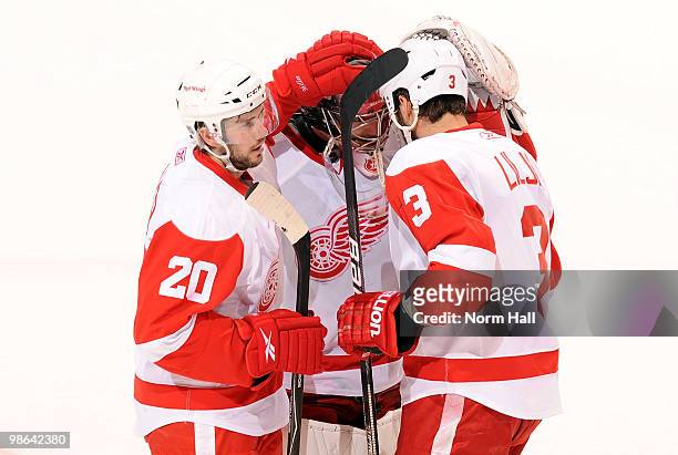 Andreas Lilja and Drew Miller of the Detroit Red Wings congratulate goaltender Jimmy Howard after a win against the Detroit Red Wings in Game Five of...