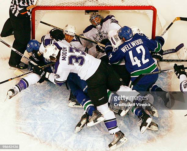 Jonathan Quick of the Los Angeles Kings lays in his crease as members of the Kings and the Canucks pile on him in his crease in Game Five of the...