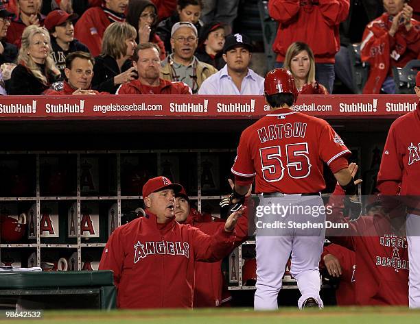 Hideki Matsui of the Los Angeles Angels of Anaheim is greeted by manager Mike Sciocia as he returns to the dugout after hitting a lead off single in...