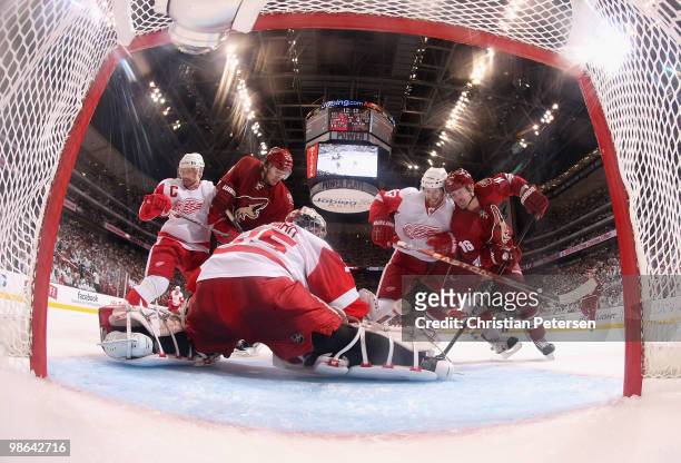 Goaltender Jimmy Howard of the Detroit Red Wings makes a pad save on the puck as Martin Hanzal and Petr Prucha of the Phoenix Coyotes battle for a...