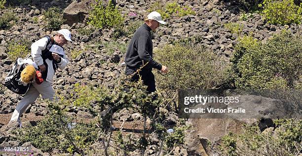 Ernie Els of South Africa and his caddie walk over volcanic rocks on the 9th hole during the Round Two of the Ballantine's Championship at Pinx Golf...
