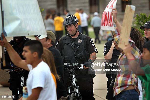 Police watch as demonstrators protest Arizona's new immigration law outside the Arizona state capitol building on April 23, 2010 in Phoenix, Arizona....