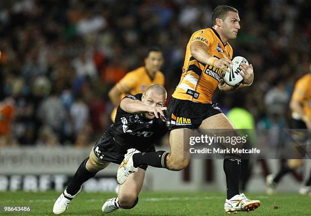 Robbie Farah of the Tigers breaks through the tackle of Luke Lewis of the Panthers during the round seven NRL match between the Penrith Panthers and...