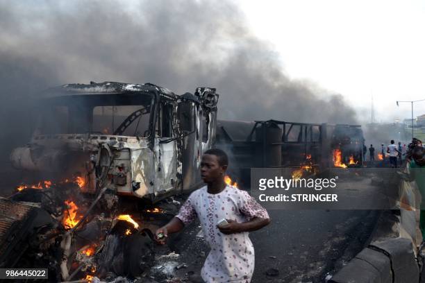 Passersby walk amid burned cars after an oil tanker exploded on a highway on June 28, 2018 in Lagos killing nine people in a huge blaze. -