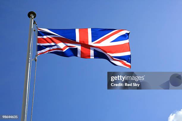 a union jack flag against a blue sky - newpremiumuk stock-fotos und bilder