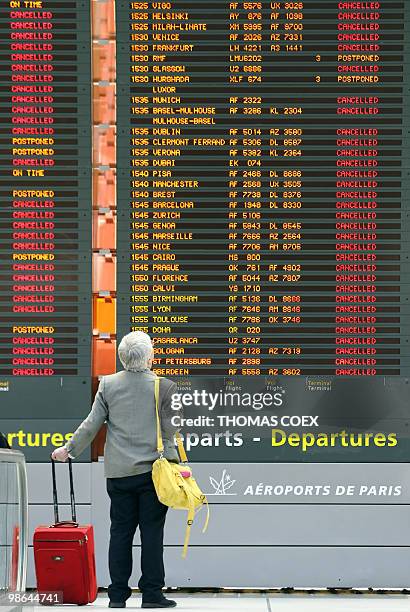 Traveller watches a giant board announcing cancelled flights on April 17 at the Roissy Charles de Gaulle airport, near Paris. Three airports in Paris...