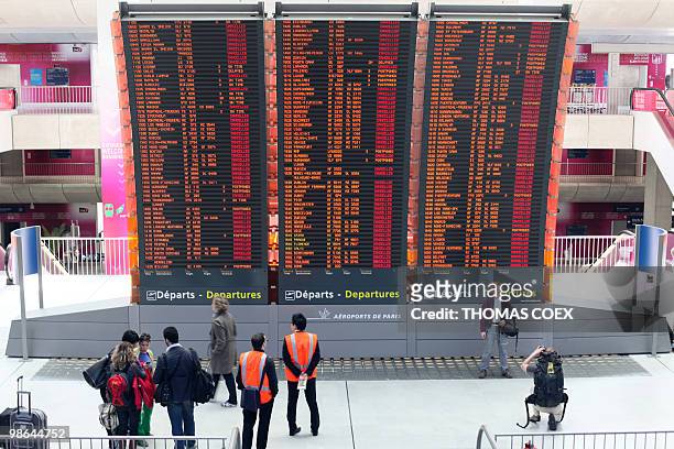 Travellers pass by a board announcing cancelled flights on April 17 at the Roissy Charles de Gaulle airport, near Paris. Three airports in Paris and...