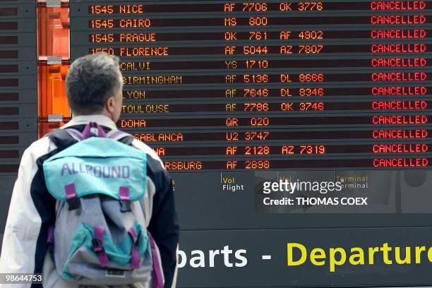 Traveller watches a board announcing cancelled flights on April 17 at the Roissy Charles de Gaulle airport, near Paris. Three airports in Paris and...