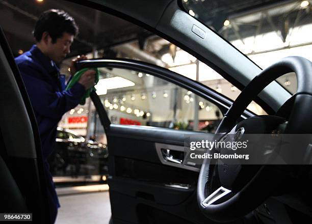 Worker polishes the window of a Jaguar XJ vehicle displayed at the Beijing Auto Show in Beijing, China, on Saturday, April 24, 2010. The show will be...