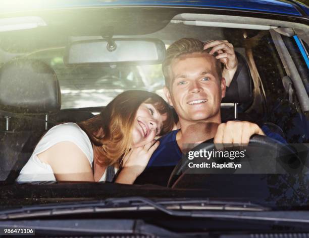 young woman embraces her driving boyfriend: risky behavior - clingy girlfriend stock pictures, royalty-free photos & images