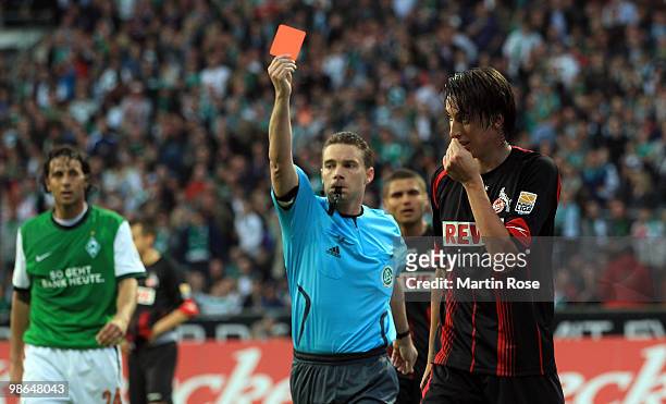 Referee Guido Winkmann shows Pedro Geromel of Koeln the red card after he stops the ball with the hand during the Bundesliga match between Werder...