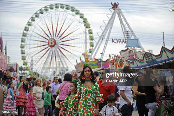 Women wearing a traditional Sevillana dresses stroll in a carnival, on April 24, 2010 during the Feria de Abril in Seville. The feria attracts...