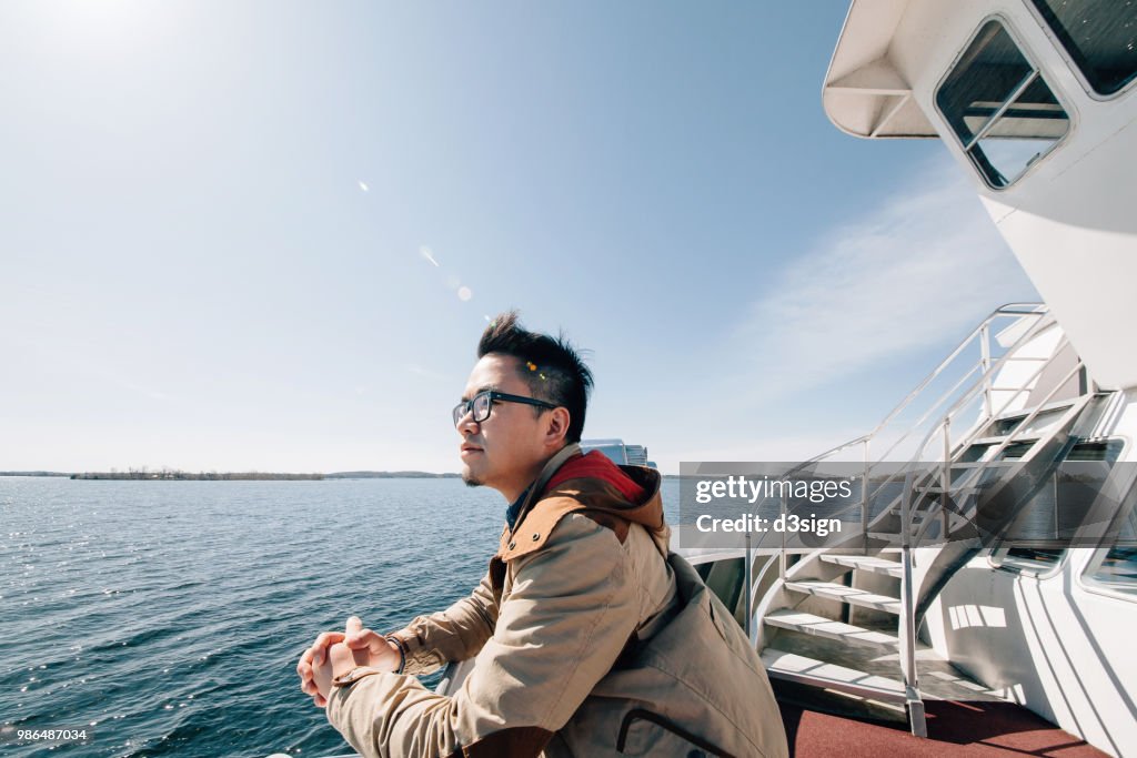 Young man traveller enjoying the sea and breeze from cruise ship