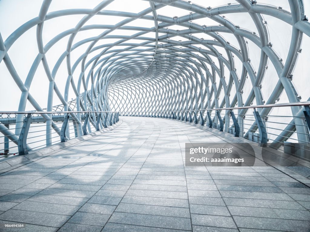 Futuristic pedestrian footbridge against sky