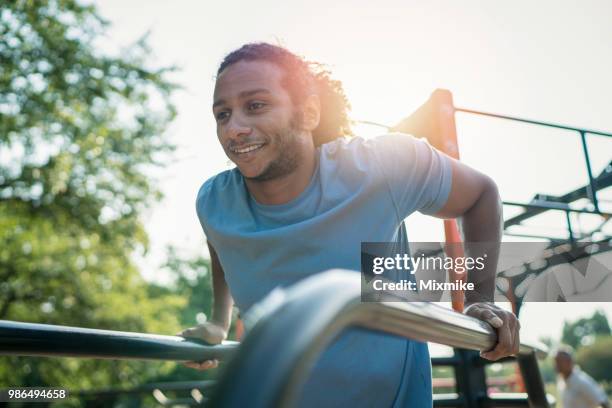 afroamerikanischen jungen männlichen training armmuskeln im park - gym equipment stock-fotos und bilder