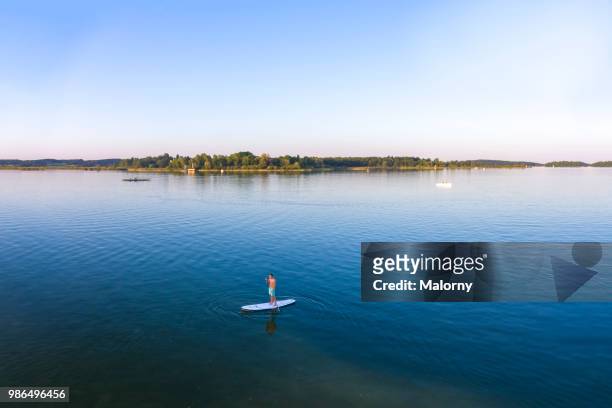 aerial view on young man paddle boarding on lake chiemsee. chiemsee, chiemgau, bavaria, germany - chiemsee stock pictures, royalty-free photos & images