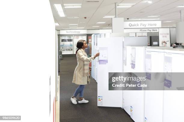 young woman in shop looking at kitchen appliances - cade stockfoto's en -beelden