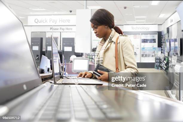 young woman in shop looking at laptops - cade stockfoto's en -beelden